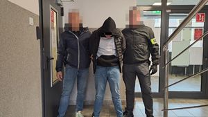 Dwaj policjanci z zatrzymanym mężczyzną w kajdankach.