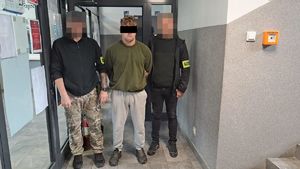 Dwaj policjanci z zatrzymanym mężczyzną w kajdankach.