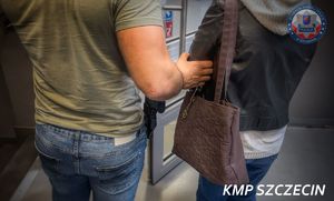 policjant idzie z zatrzymaną.