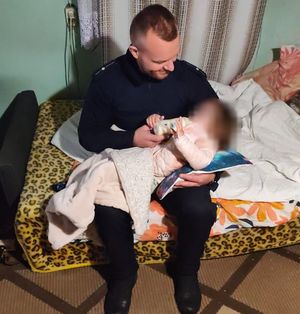 policjant trzyma na rękach i karmi dziecko.