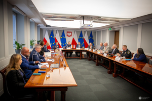 Przedstawiciele amerykańskich organów ścigania i środowiska akademickiego wraz z polskimi funkcjonariuszami podczas spotkania w Komendzie Głównej Policji przy stole w sali generalskiej.