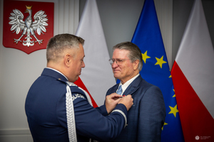 Zastępca Komendanta Głównego policji przypina mężczyźnie medal.