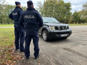 Uczestnicy kursu specjalistycznego dla policjantów. Dwaj policjanci stoją przy samochodzie osobowym.