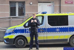Policjant stoi przy radiowozie.