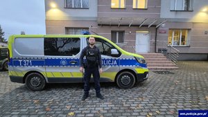 Policjant stoi przy radiowozie.