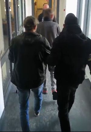Policjanci i zatrzymani idą korytarzem.