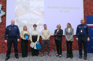 dzieci z policjantami pozują na tle swoich prac.