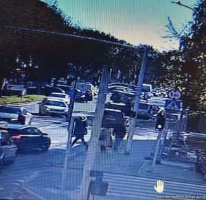 Stopklatka z nagrania monitoringu przedstawia ruch uliczny - samochody na drodze i pieszych na chodniku.