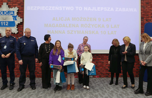 dzieci z policjantami pozują na tle swoich prac.