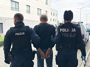 Dwaj policjanci prowadzą zatrzymanego mężczyznę.