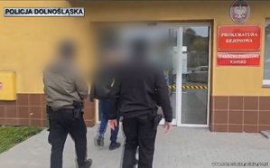 Dwaj policjanci prowadzą zatrzymaną.