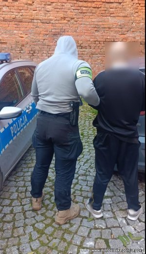 Policjanci prowadzą zatrzymanego.