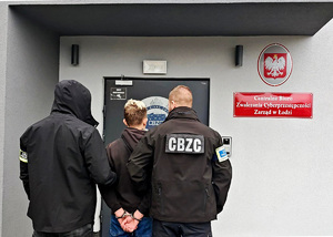 Dwaj policjanci prowadzą zatrzymanego.