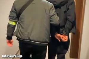 Policjant prowadzi zatrzymanego mężczyznę.