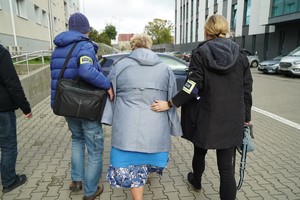 Policjanci stoją z zatrzymaną kobietą.