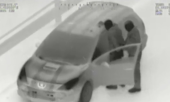 Zdjęcie w podczerwieni wykonane ze śmigłowca, Widoczny pojazd i dwie osoby przy nim.