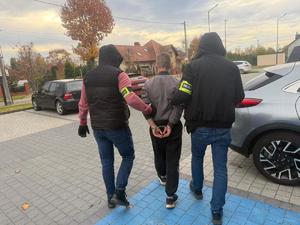 Zatrzymany prowadzony przez dwóch policjantów.