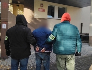 Dwaj policjanci prowadza zatrzymanego mężczyznę.