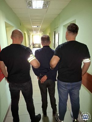 policjanci prowadzą zatrzymanego.