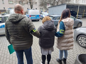 Policjant i policjantka prowadza zatrzymaną osobę.