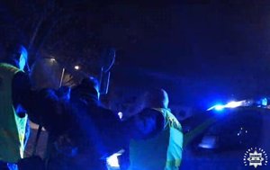 Pora nocna. Dwaj funkcjonariusze prowadza zatrzymanego.
