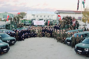 Grupa policjantów i żołnierzy pozująca do zdjęcia. Obok nich pojazdy wojskowe i policyjne.
