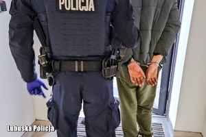 Policjant prowadzi zatrzymanego.