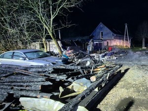 Elementy spalonego budynku. Obok samochód.