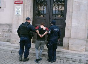 Dwaj policjanci prowadza zatrzymanego.
