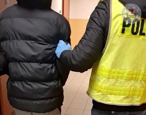 Zdjęcie kolorowe. Policjant z zatrzymanym.