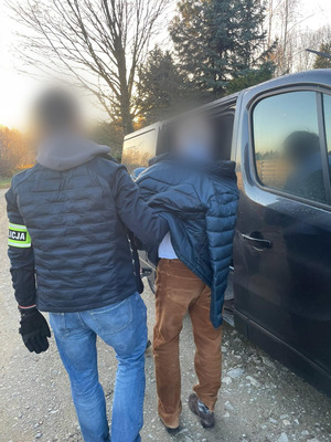 Policjant prowadzi zatrzymanego.