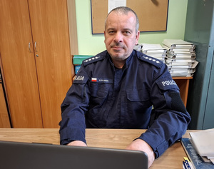 Asp. szt. Grzegorz Pilarski siedzi przy biurku.
