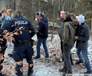 Mężczyźni na dworze i policjant między nimi.