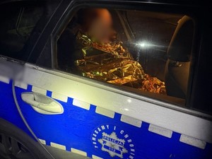 Siedzący w radiowozie mężczyzna opatulony w koc termiczny.