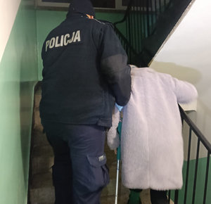Policjant prowadzi starszą osobę.