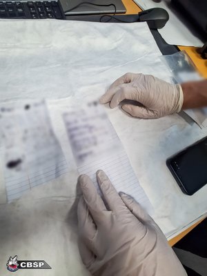 Dłonie w rękawiczkach i zablurowany tekst na kartkach.