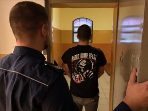 policjant stoi za zatrzymanym.