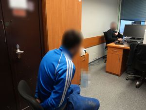 Zatrzymany mężczyzna siedzi w pomieszczeniu biurowym z policjantem operacyjnym.
