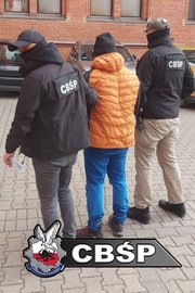 Policjanci prowadzą zatrzymanego.