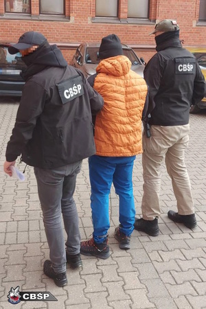 Policjanci prowadzą zatrzymanego.