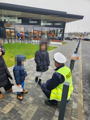 Dwójka odnalezionych dzieci, obok nich kuca policjant.