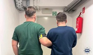 policjant stoi z zatrzymanym.