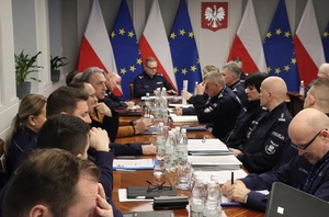 Uczestnicy spotkania siedzą przy owalnym stole.