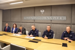 Komendant Główny Policji i Prokurator Krajowy i inni policjanci siedzą przy stole.