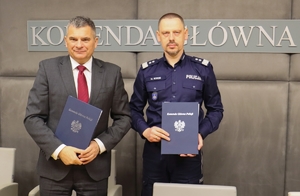 Komendant Główny Policji i Prokurator Krajowy trzymają w dłoniach podpisane porozumienie.