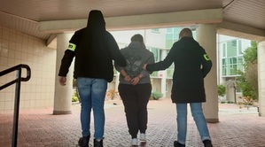 policjanci prowadzą zatrzymaną po schodach.