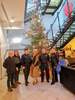 Policjanci z Biura Prewencji KGP i pracownicy pozują do zdjęcia na tle świątecznej choinki.