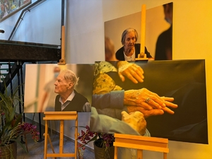 Trzy wielkoformatowe zdjęcia na sztalugach przedstawiające seniora, seniorkę i dłonie starszych osób.