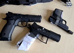 Trzy sztuki broni krótkiej leżące na biurku.