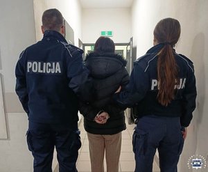 dwoje policjantów prowadzi zatrzymaną przez korytarz.